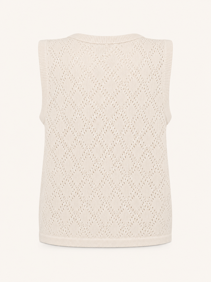 A sleeveless knit vest in a warm cream or off-white color, featuring an openwork diamond lattice pattern and ribbed trim, shown against a plain light background.
