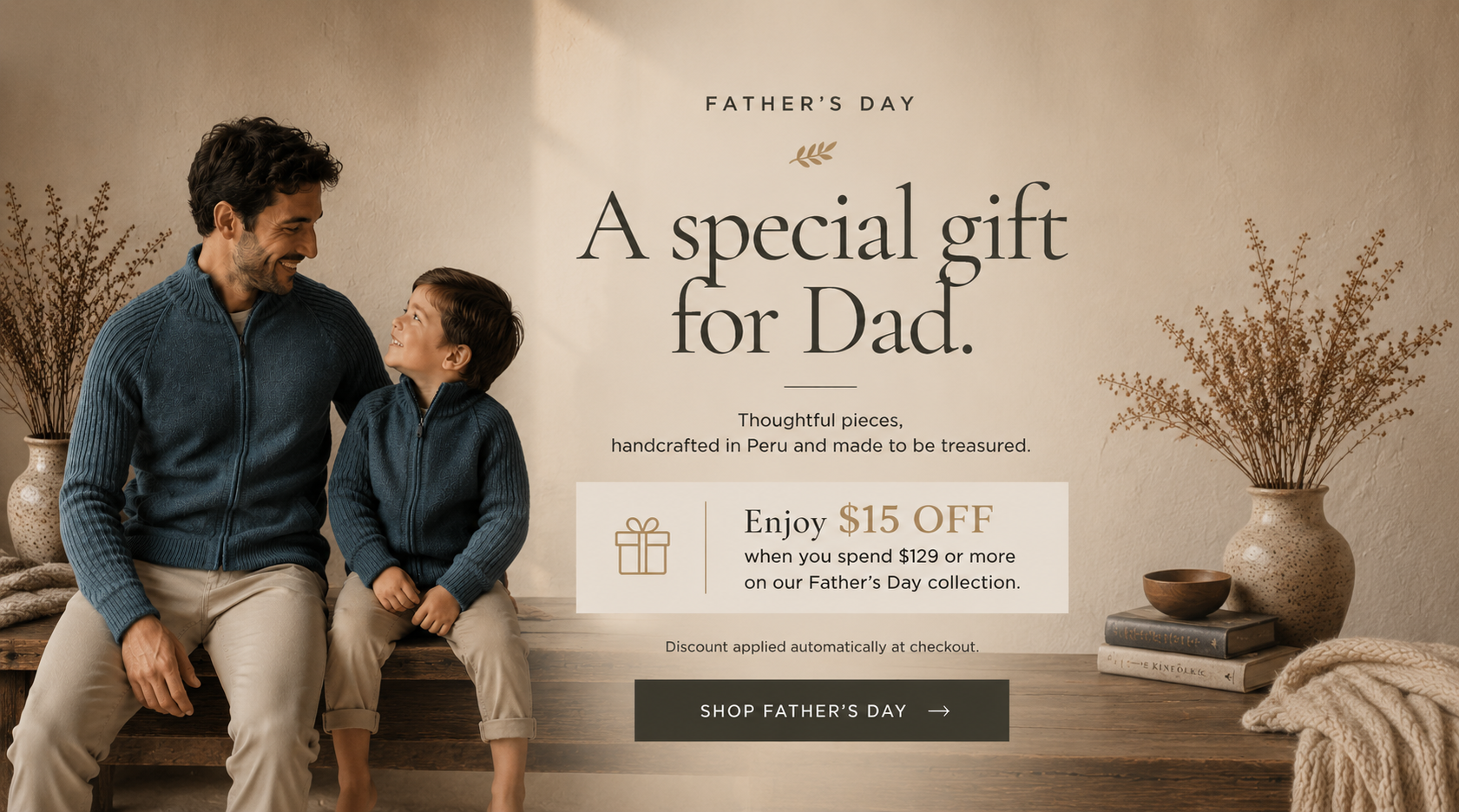 A Father's Day promotional banner featuring a man and a child sitting together on a bench, wearing matching dark blue knit tops. The background is a warm beige wall with decorative dried plants in vases, books, and a throw blanket.